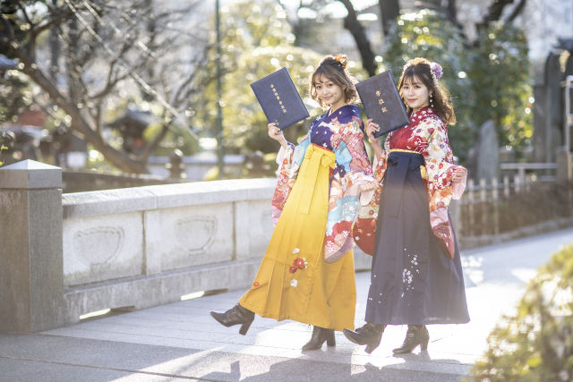 卒業証書を手に持った袴を着た二人の女性